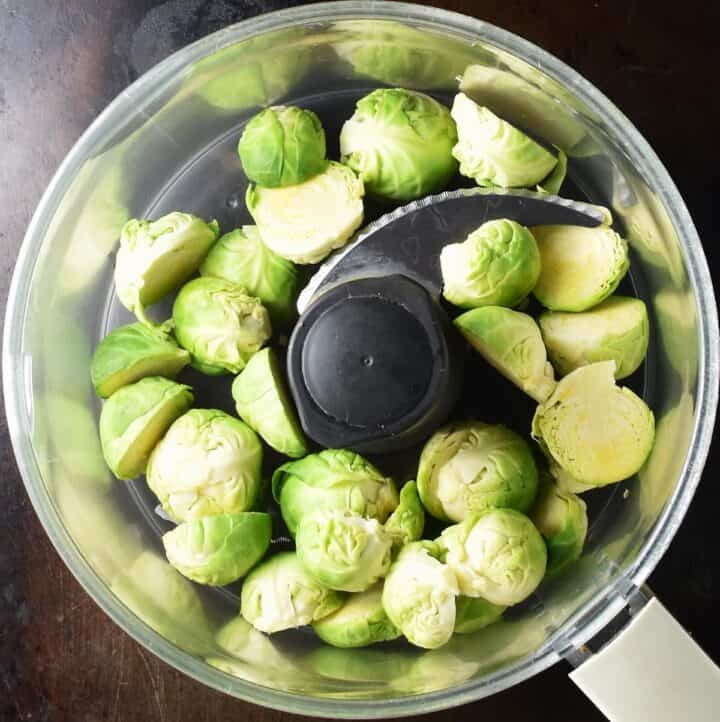 Halved brussels sprouts in food processor.