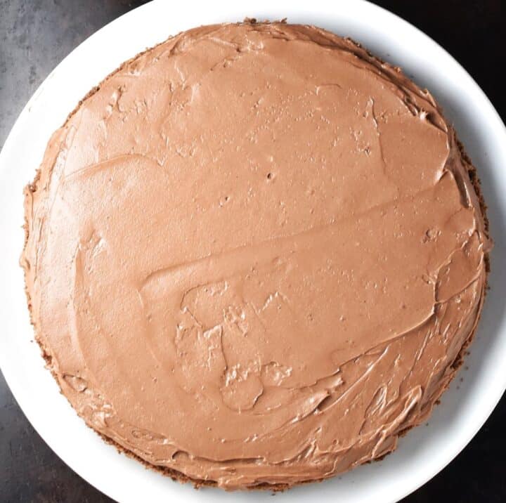 Top down view of hazelnut cake with chocolate frosting on plate.
