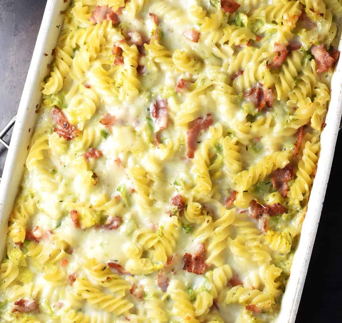 Oven baked brussels sprouts pasta with creamy sauce in rectangular dish.