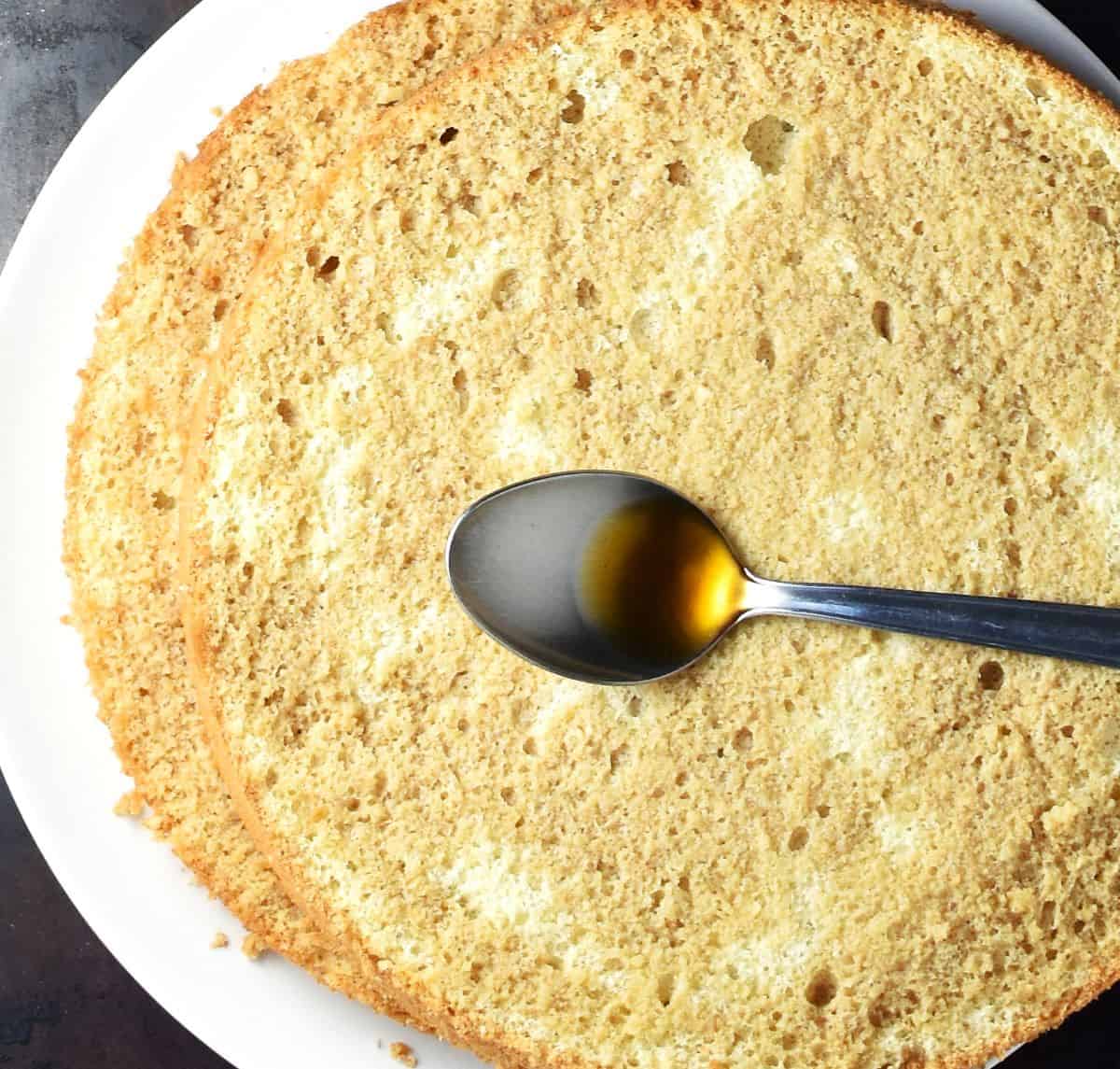 Hazelnut sponge rounds infused with coffee on plate with spoon.