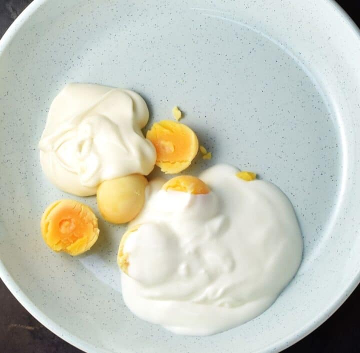 Egg yolks and yogurt in large shallow blue bowl.