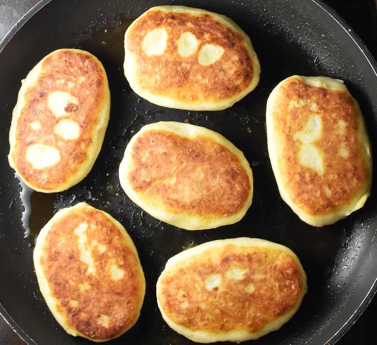 Top down view of browned potato cakes on top of large pan.