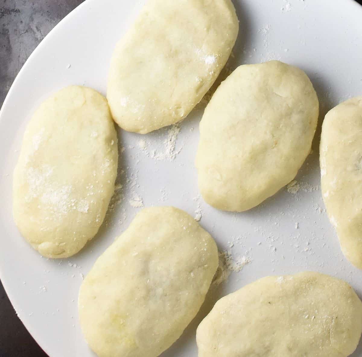 Stuffed potato cakes on top of plate dusted with flour.
