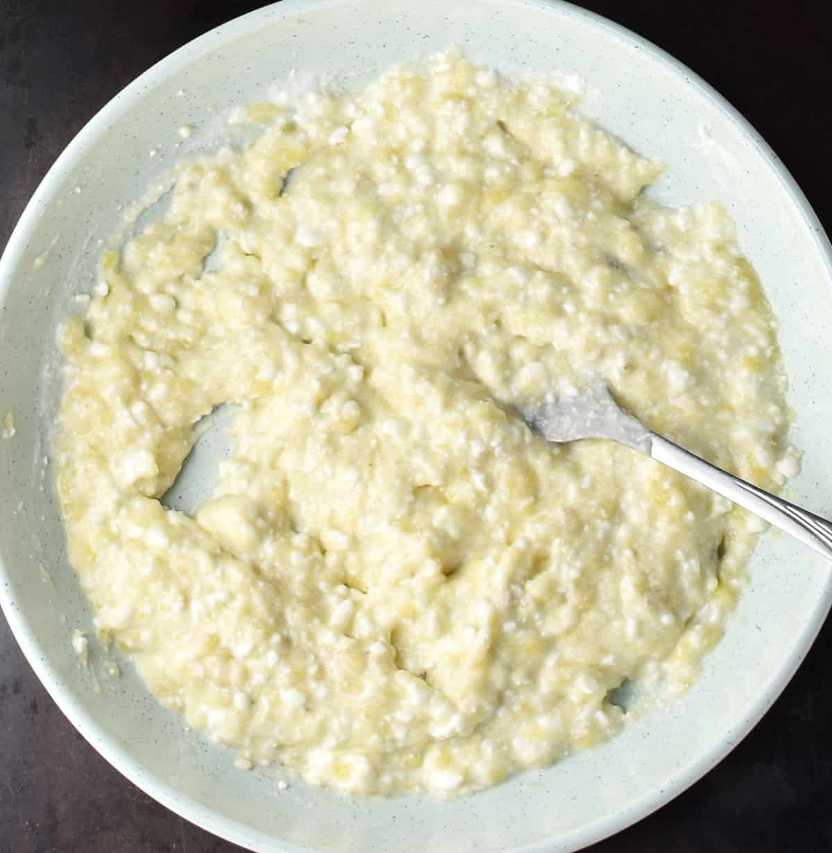 Creamy banana and cottage cheese mixture with fork in blue bowl.