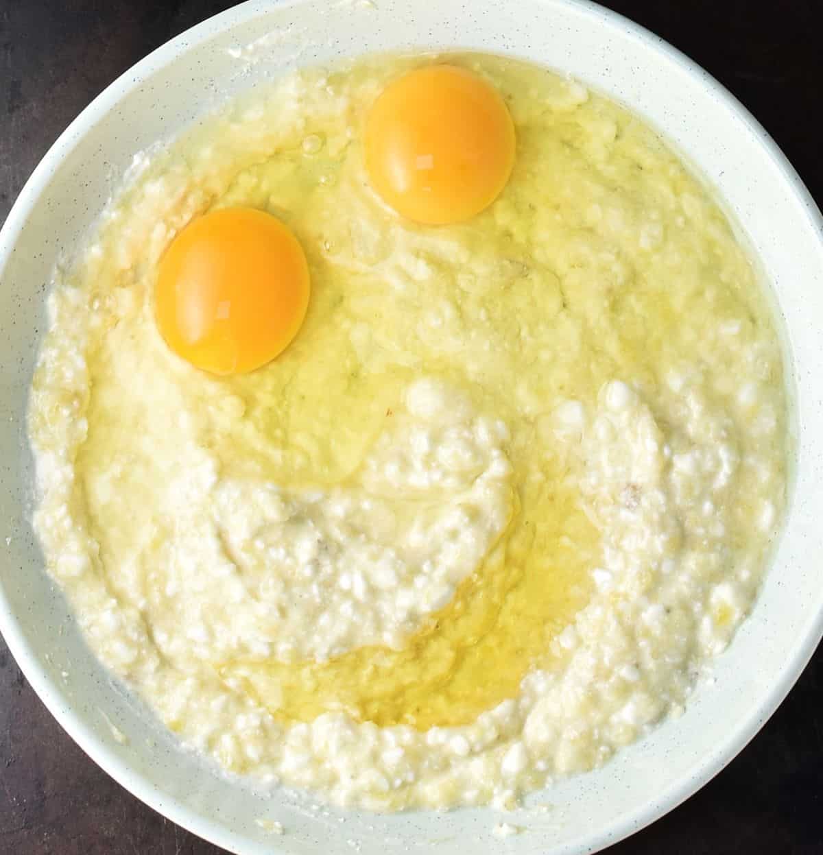 Cottage cheese banana mash with 2 raw eggs in bowl.
