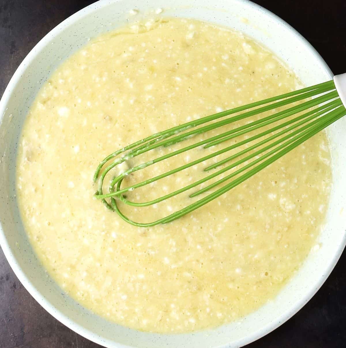 Creamy pancake mixture with whisk in blue bowl.