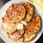Top down view of cottage cheese banana pancakes with knob of butter on speckled plate.