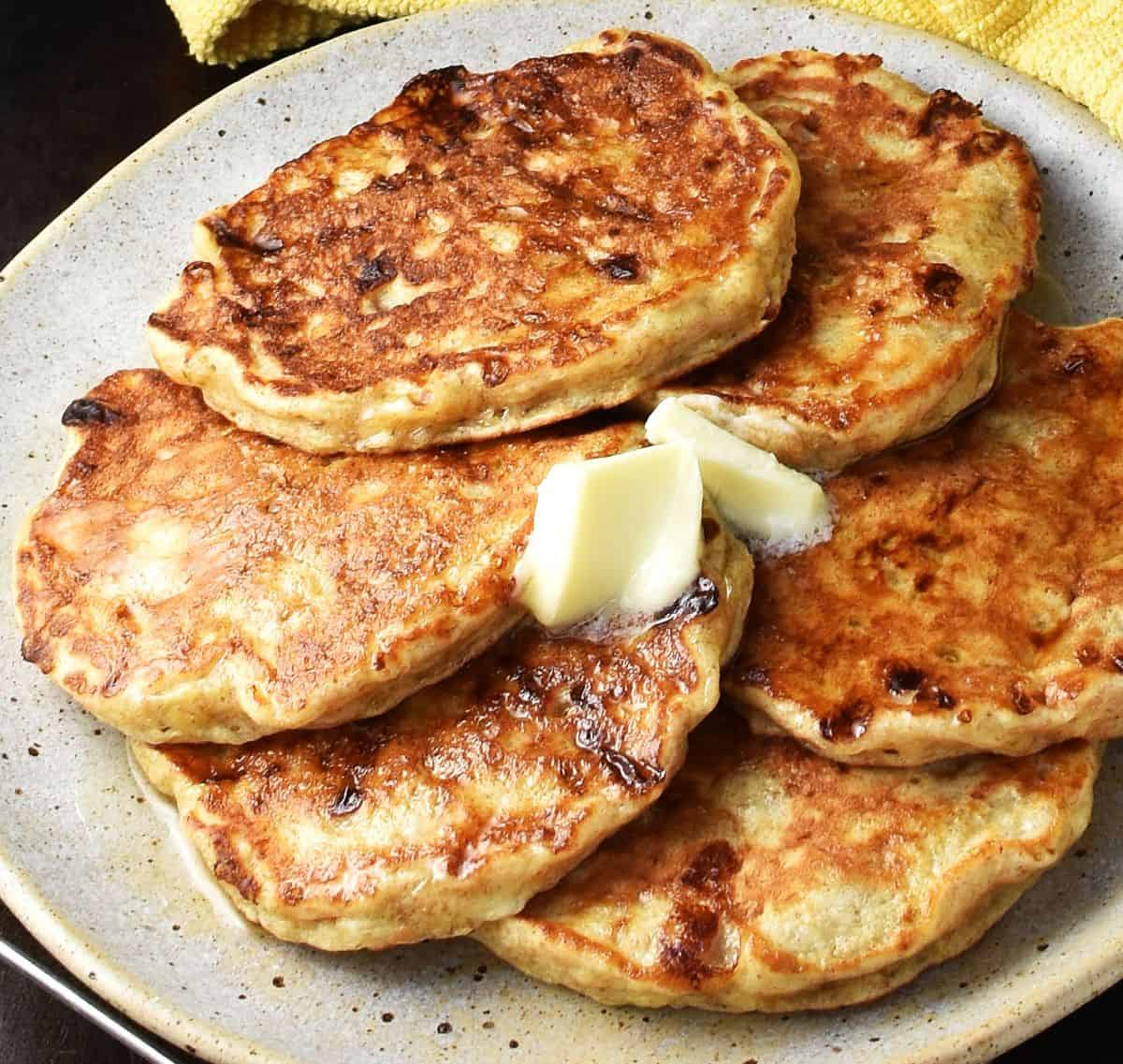 Close-up view of banana cottage cheese pancakes with butter on plate.