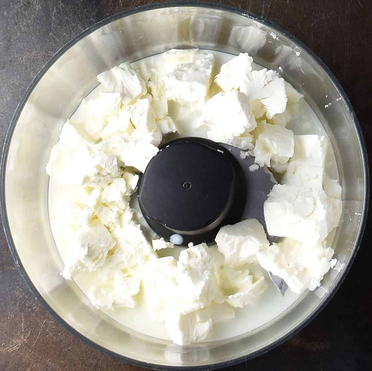 Crumbled feta and milk in food processor bowl.