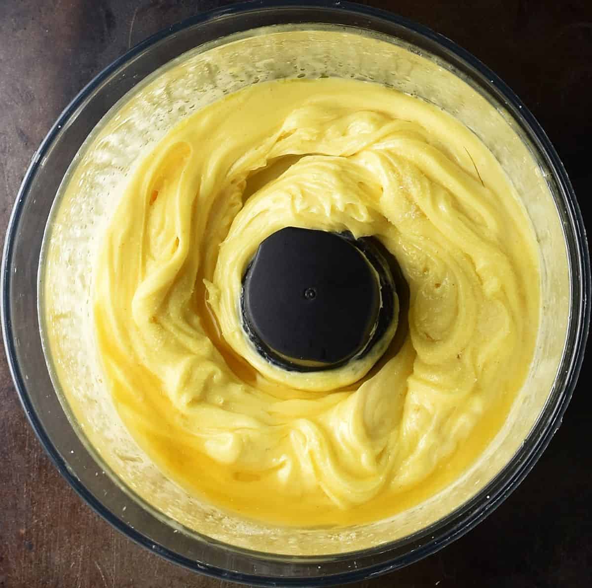 Top down view of creamy mayo in food processor.