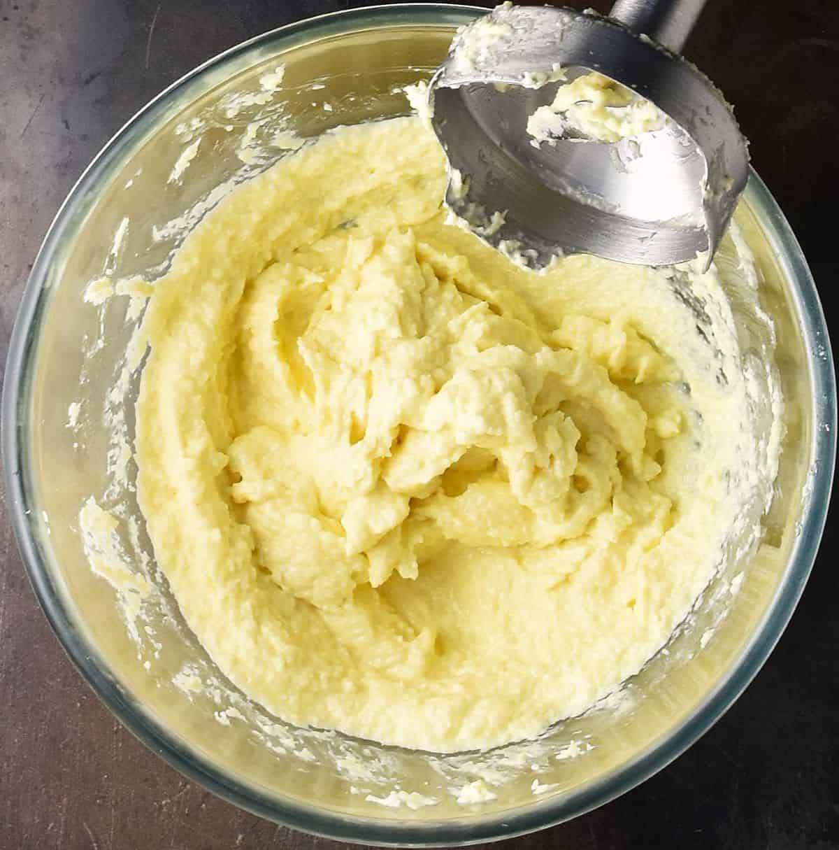 Pureed horseradish with mayo in glass bowl with blender end.
