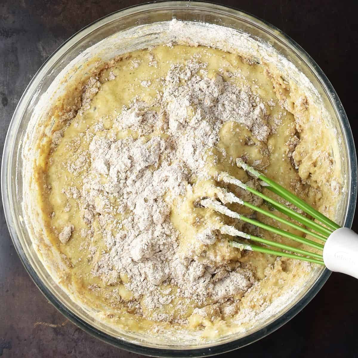 Mixing flour into cottage cheese banana muffin batter in large bowl with whisk.