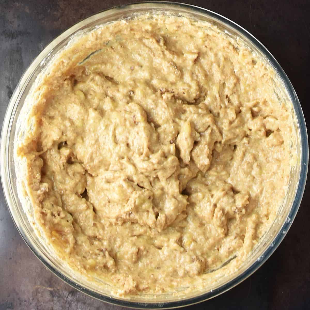 Top down view of thick banana cottage cheese muffin batter in glass bowl.