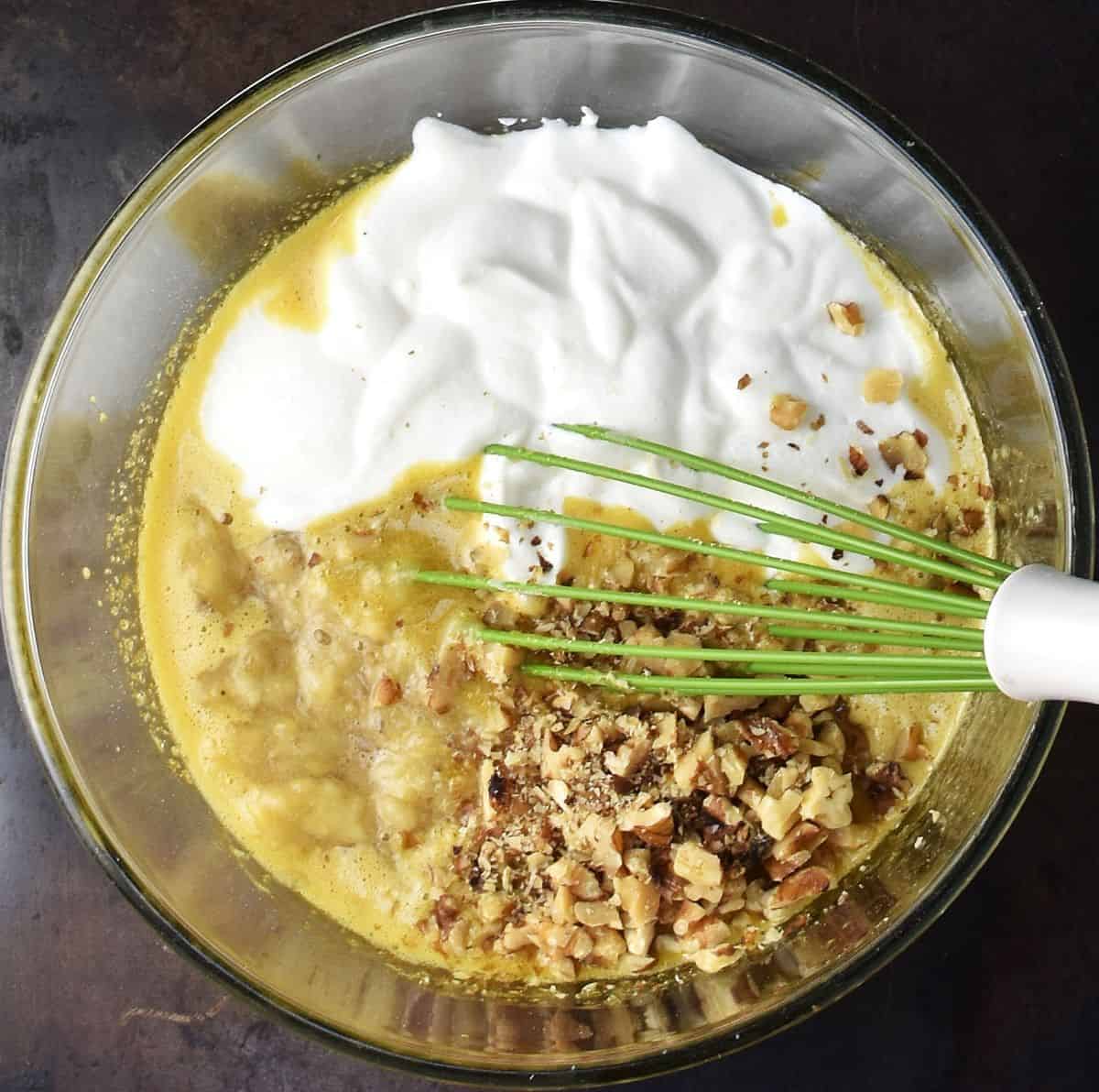 Creamed cottage cheese, mashed banana and chopped walnuts in muffin batter in glass bowl with whisk.