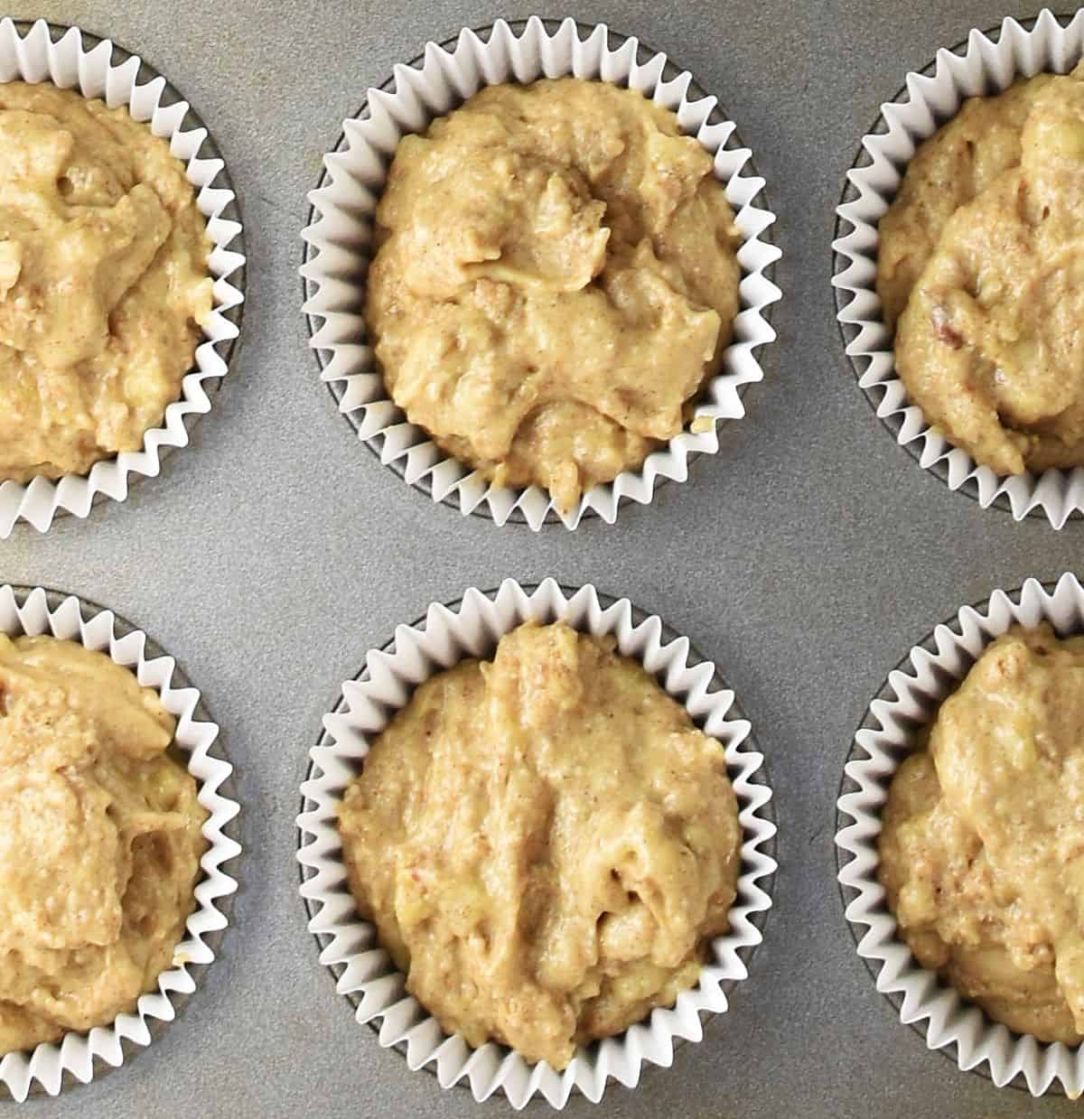 Top down view of cottage cheese and banana batter in muffin cases in pan.