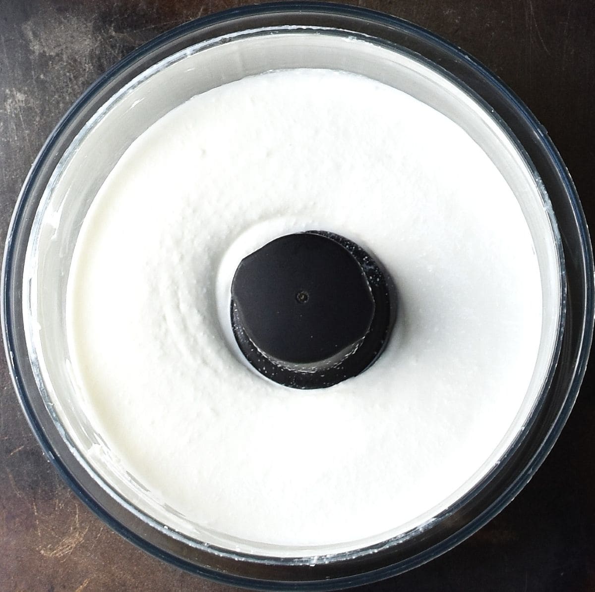 Top down view of whipped cottage cheese in food processor bowl.