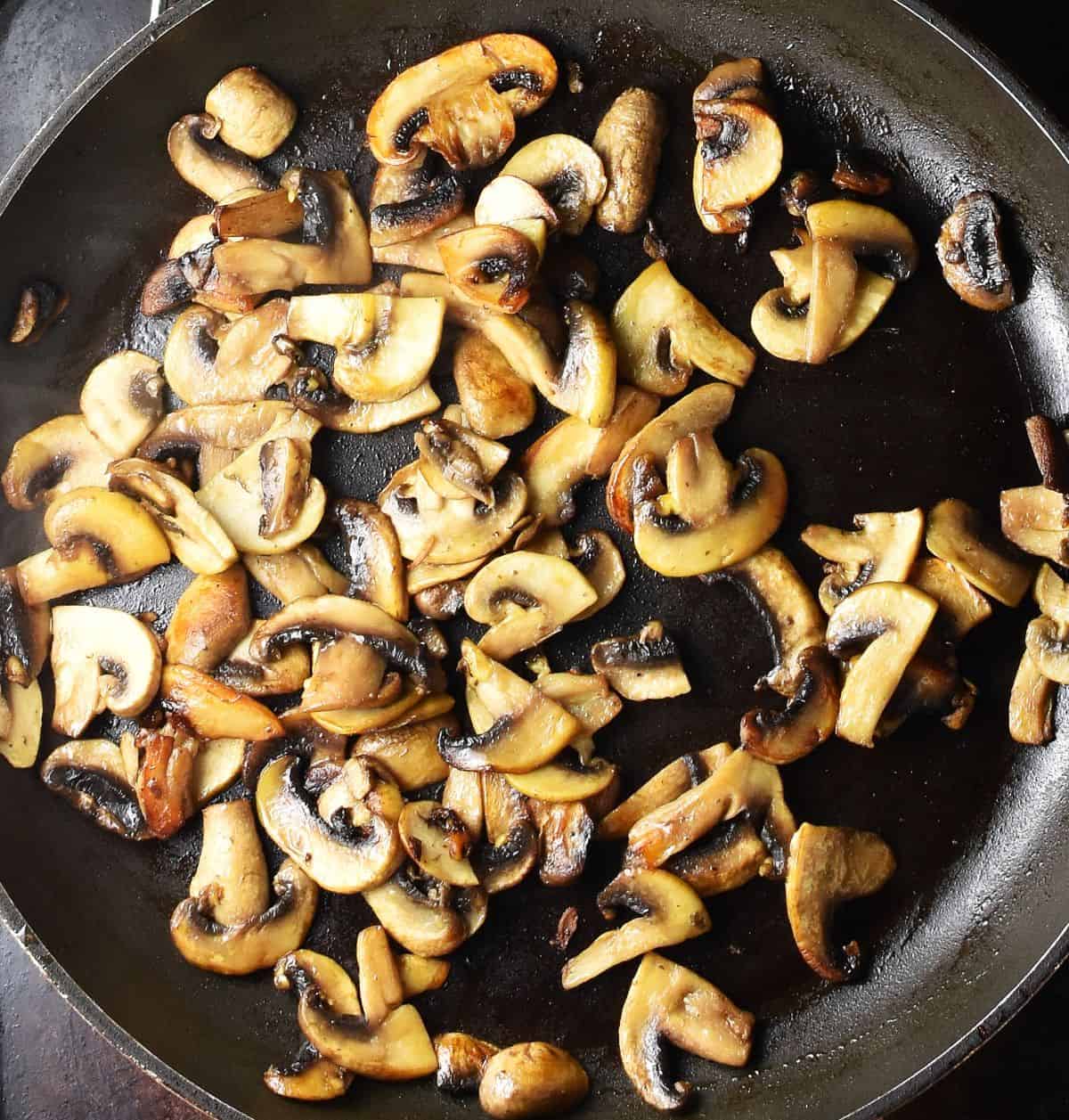 Top down view of browned sliced mushrooms for Polish soup in pan.