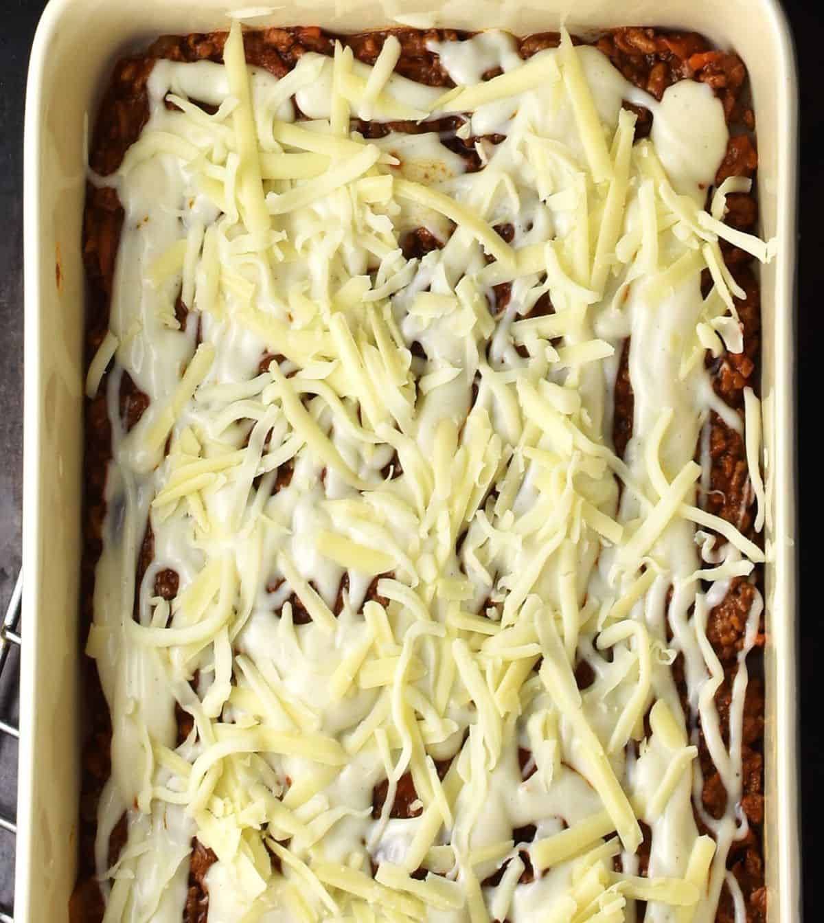 Top down view of assembling potato meat lasagna with cheese on top.