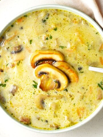 Top down view of Polish mushroom soup in white bowl with spoon.