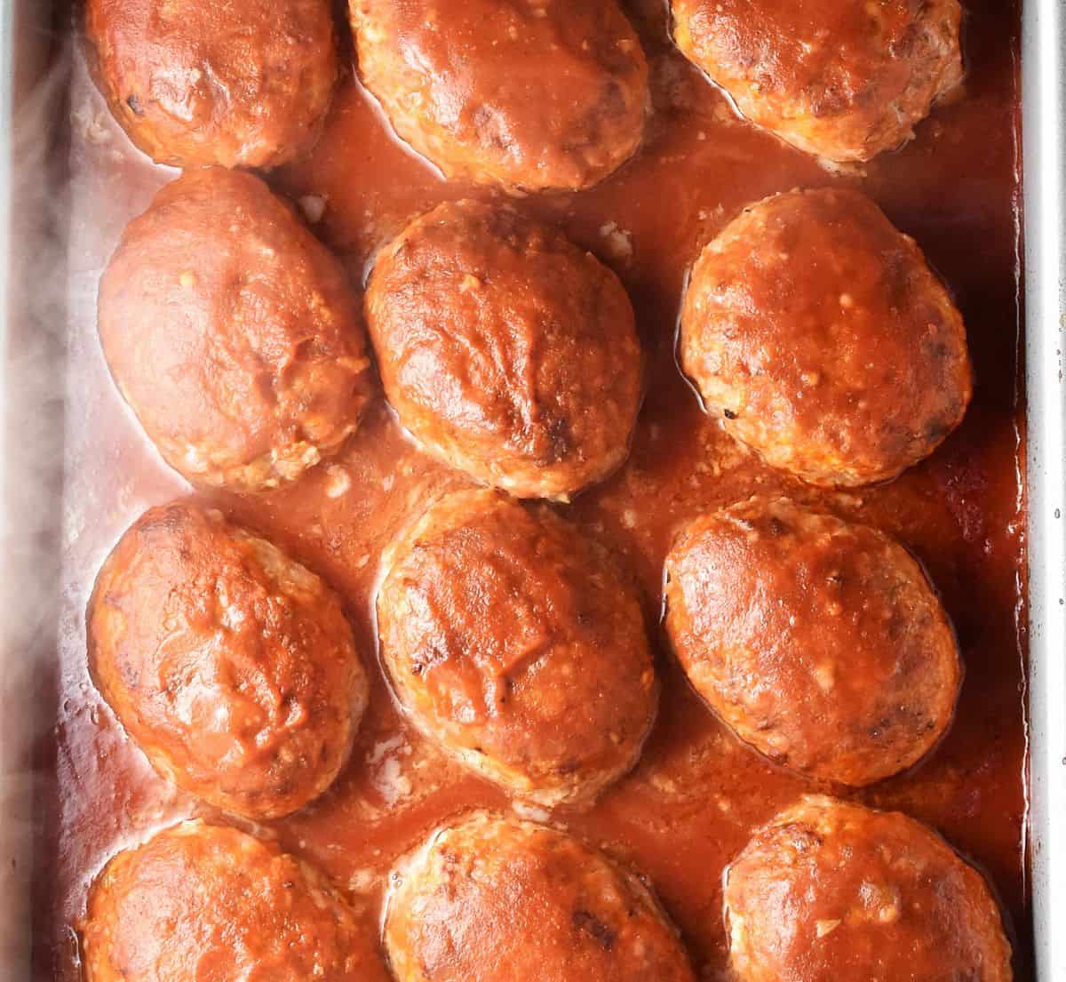 Baked lazy cabbage rolls in tomato sauce with steam visible in large shallow dish.