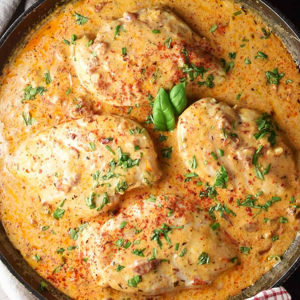 Top down close-up view of 4 healthy marry me chicken breasts in creamy sauce in pan.