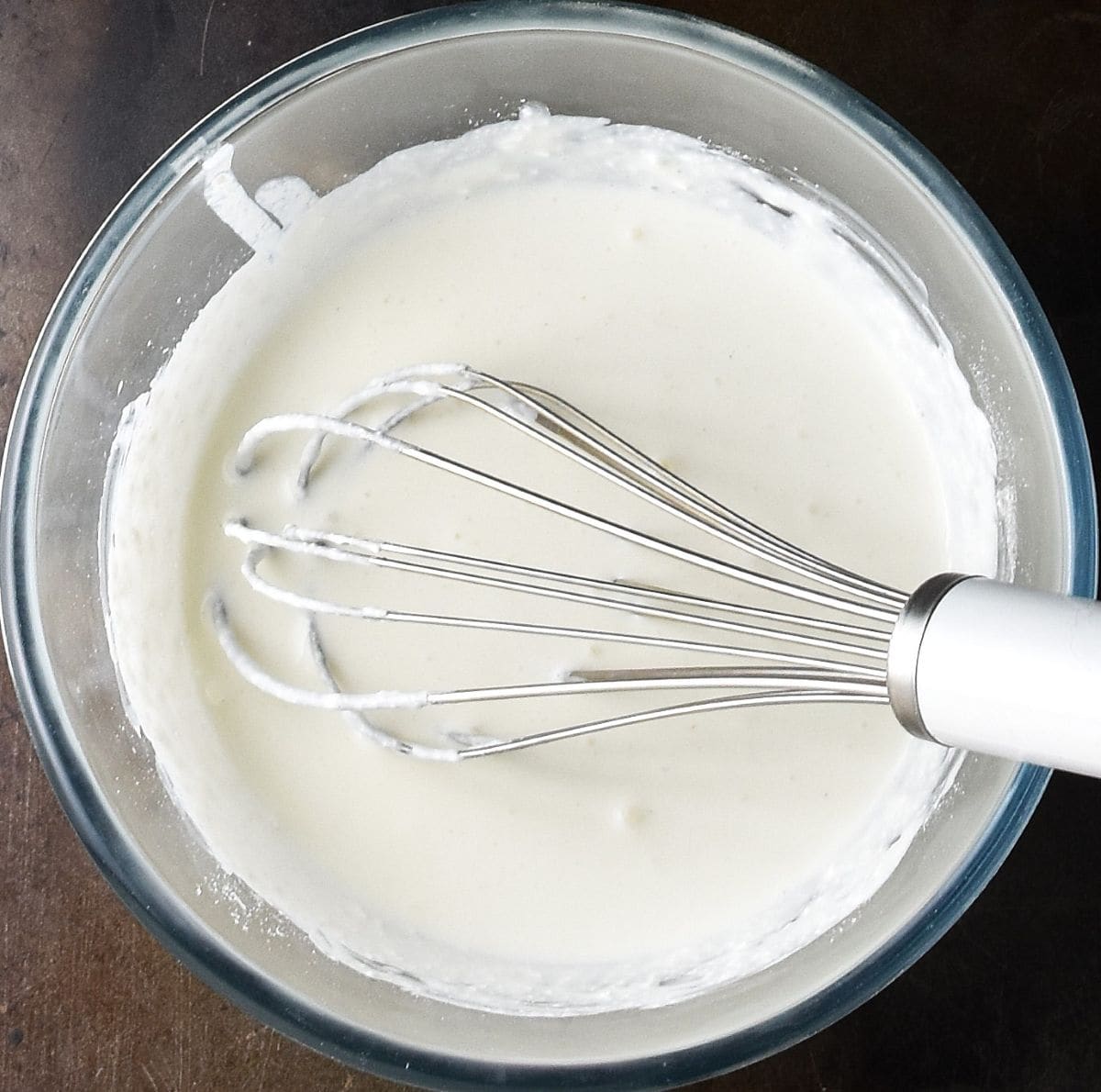 Creamy cottage cheese mixture with whisk in glass bowl.