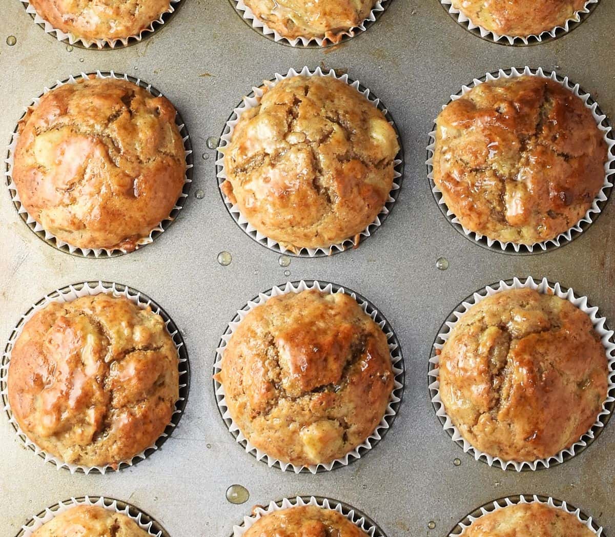 Top down view of baked pear muffin in white cases in pan.