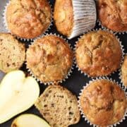 Top down view of pear muffins in white paper cases and halved pear.