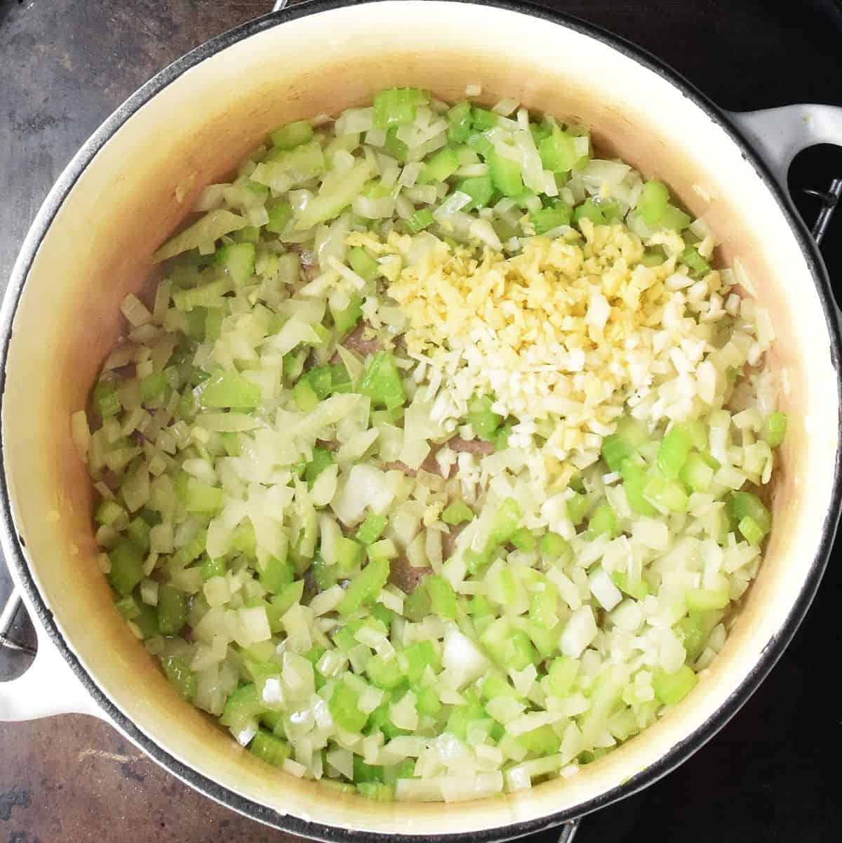 Finely chopped onion and celery in large white pot.