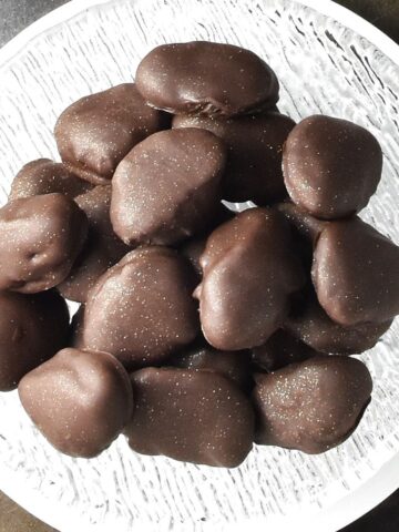 Top down view of chocolate covered prunes in glass bowl.