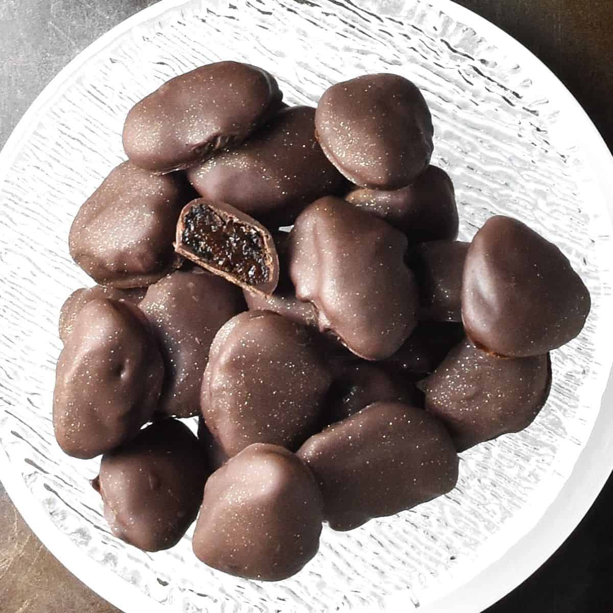 Top down view of chocolate dipped prunes in small glass bowl.