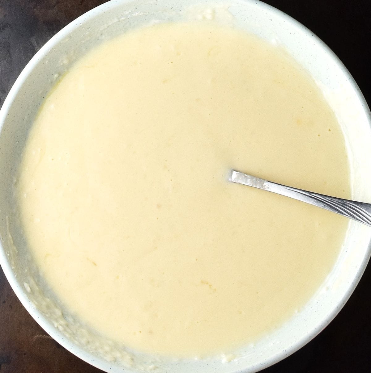 Creamy potato egg mixture with fork in large shallow bowl.