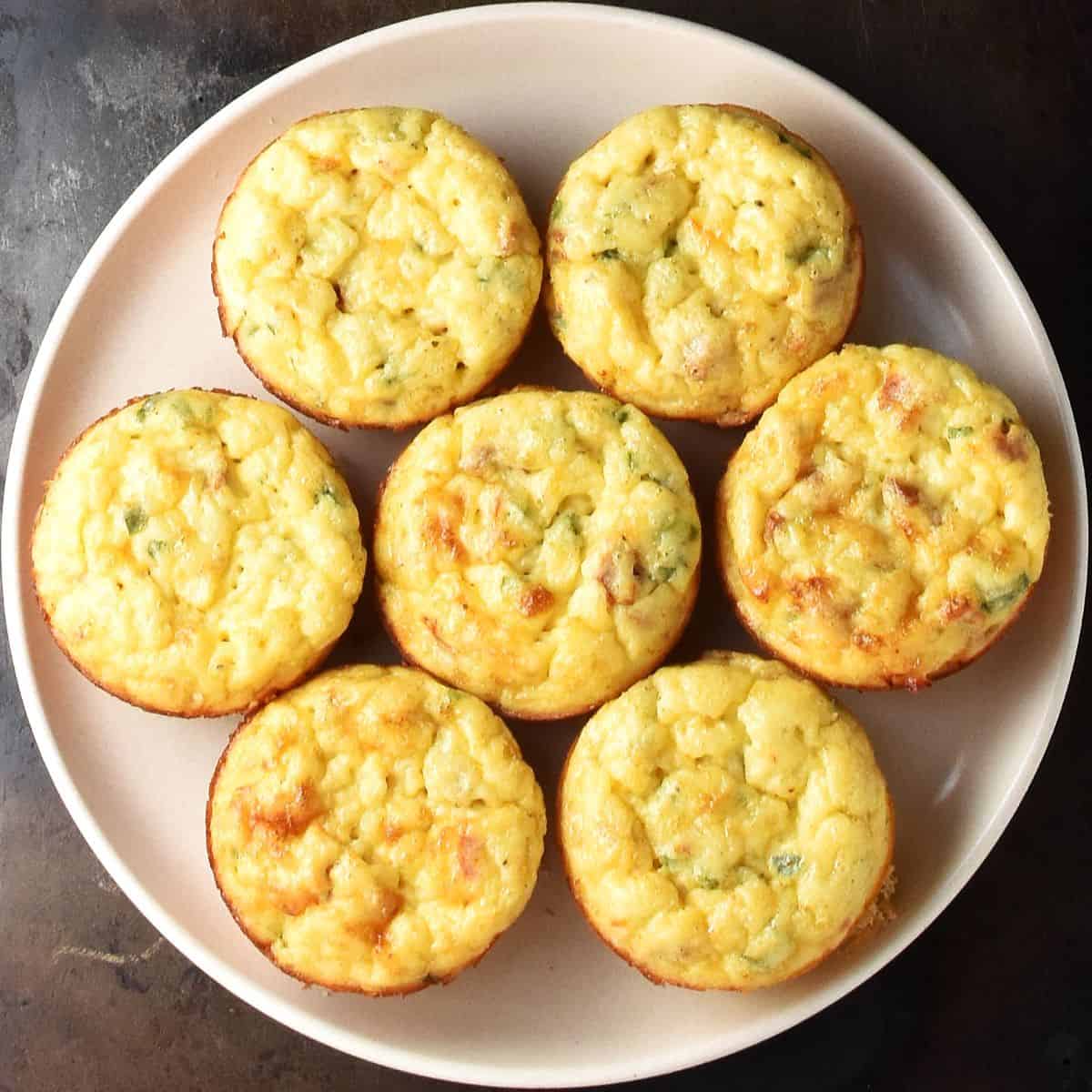 Top down view of 7 potato egg muffins on pink plate.
