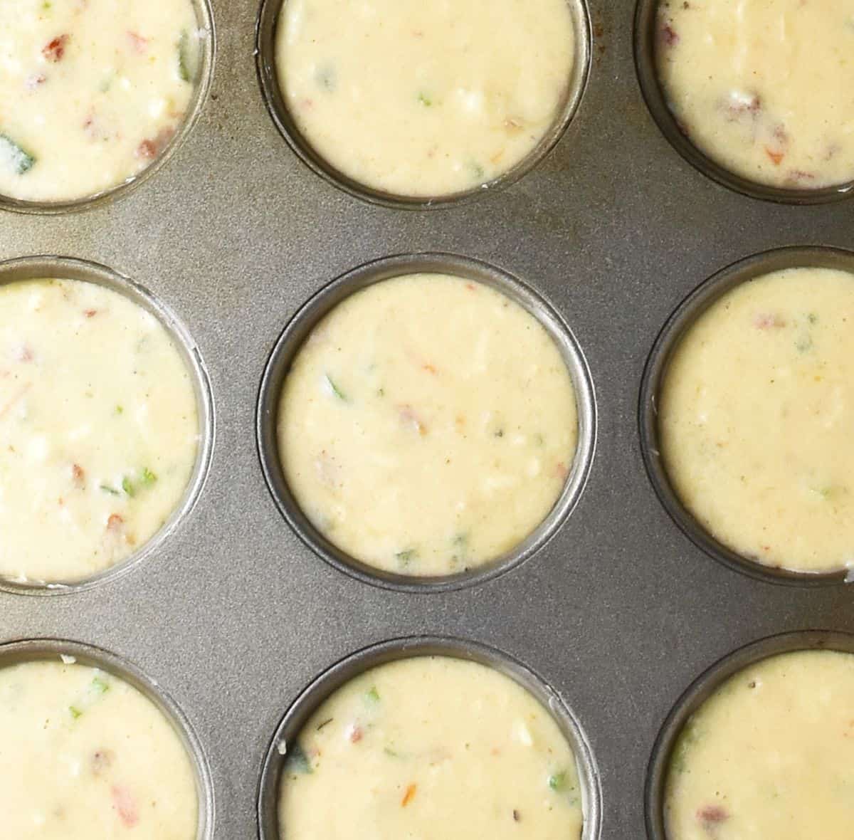 Top down view of egg and mashed potato batter in muffin pan.