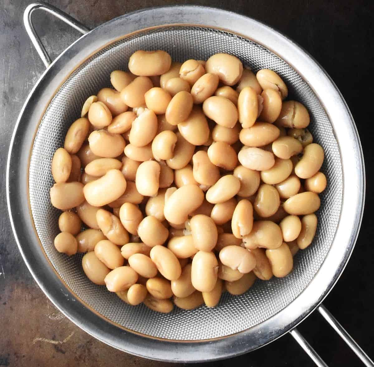 Butter beans in metal strainer.