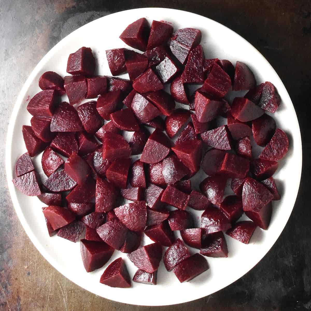 Top down view of cubed pickled beets on white plate.