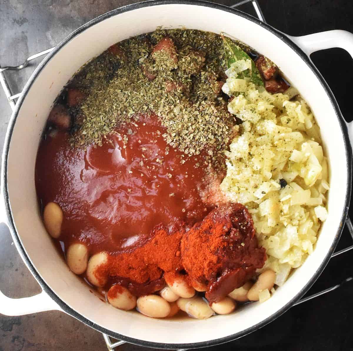 Ingredients for Polish beans assembled in large white pot.